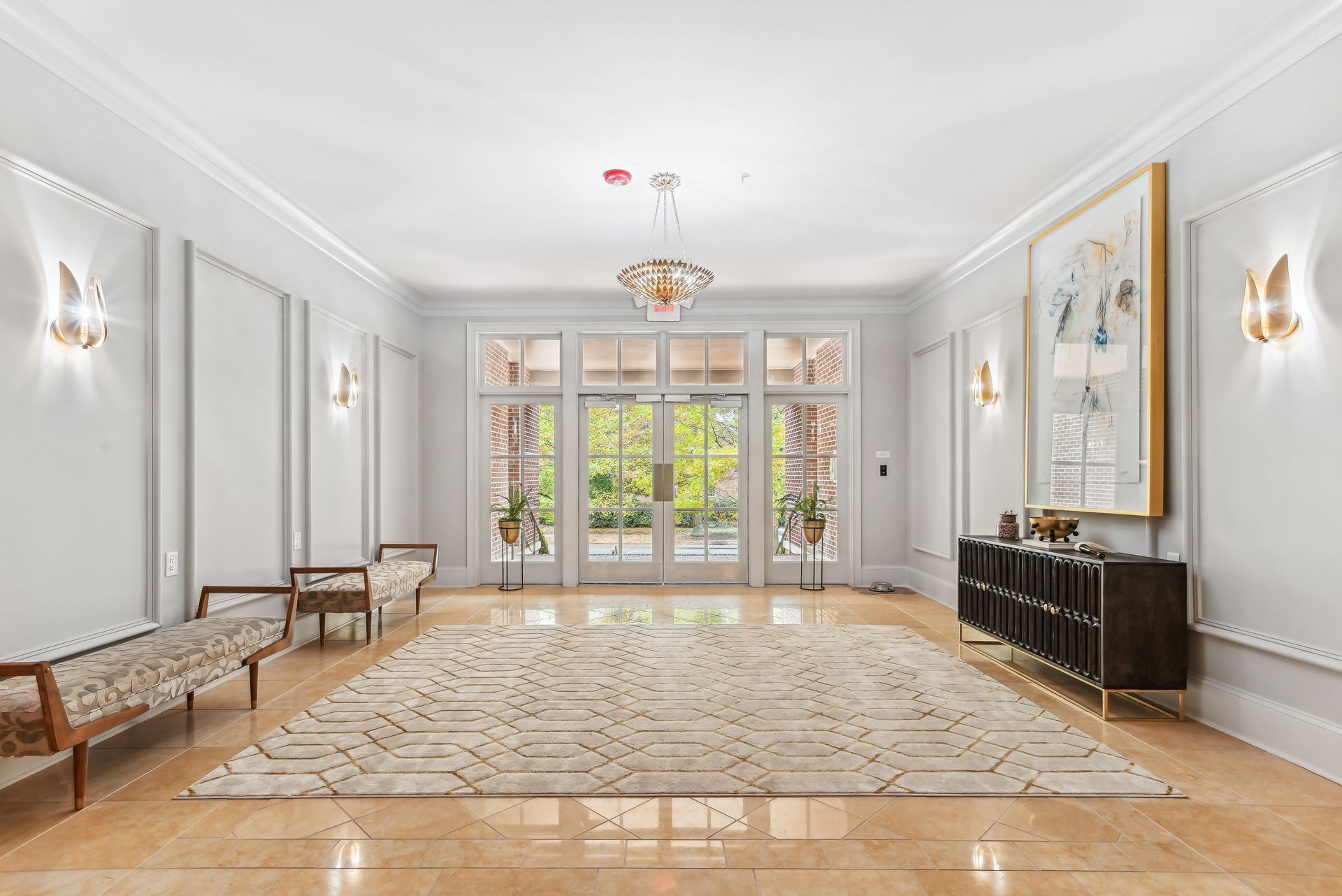Elegant entryway with light walls, large rug, glass doors, and seating.