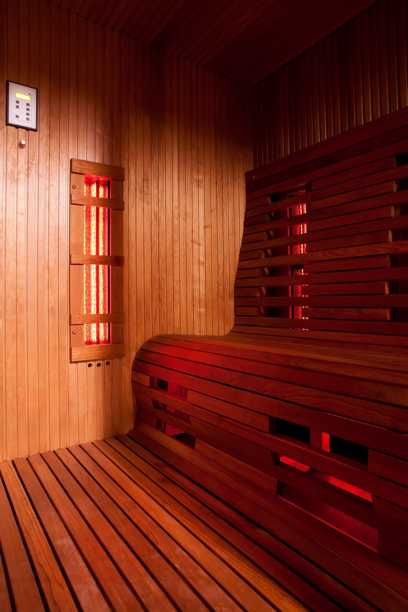 Wooden sauna interior with red infrared lights and bench.