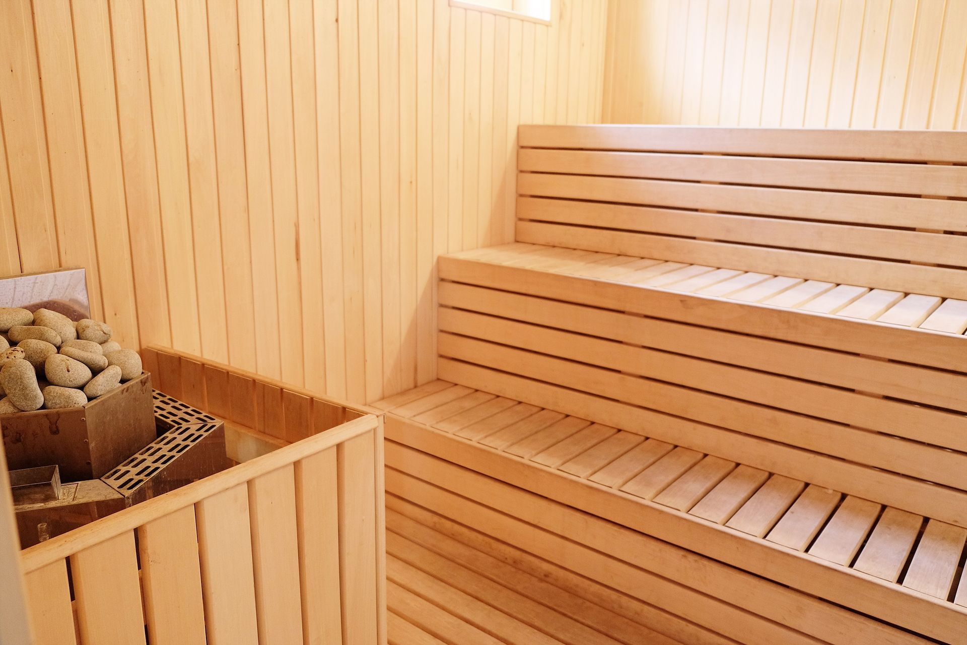 Wooden sauna interior with tiered benches and a rock heater.