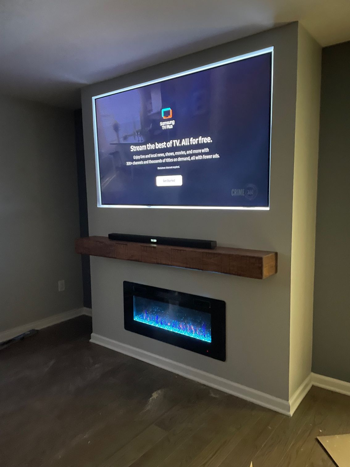 Gray accent wall with mounted TV, fireplace, and wooden shelf.