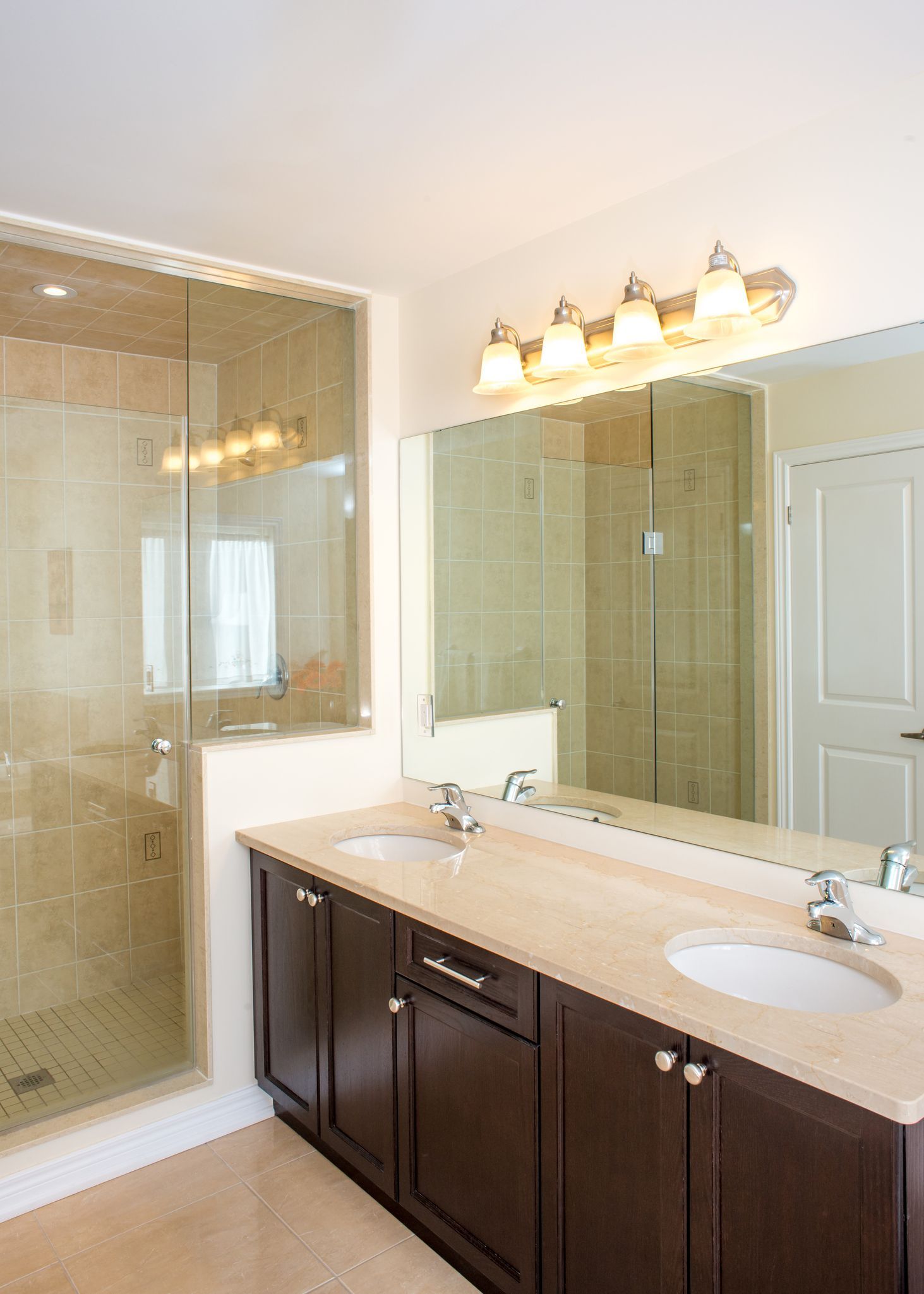 Bathroom with a double sink vanity, large mirror, and a glass-enclosed shower.