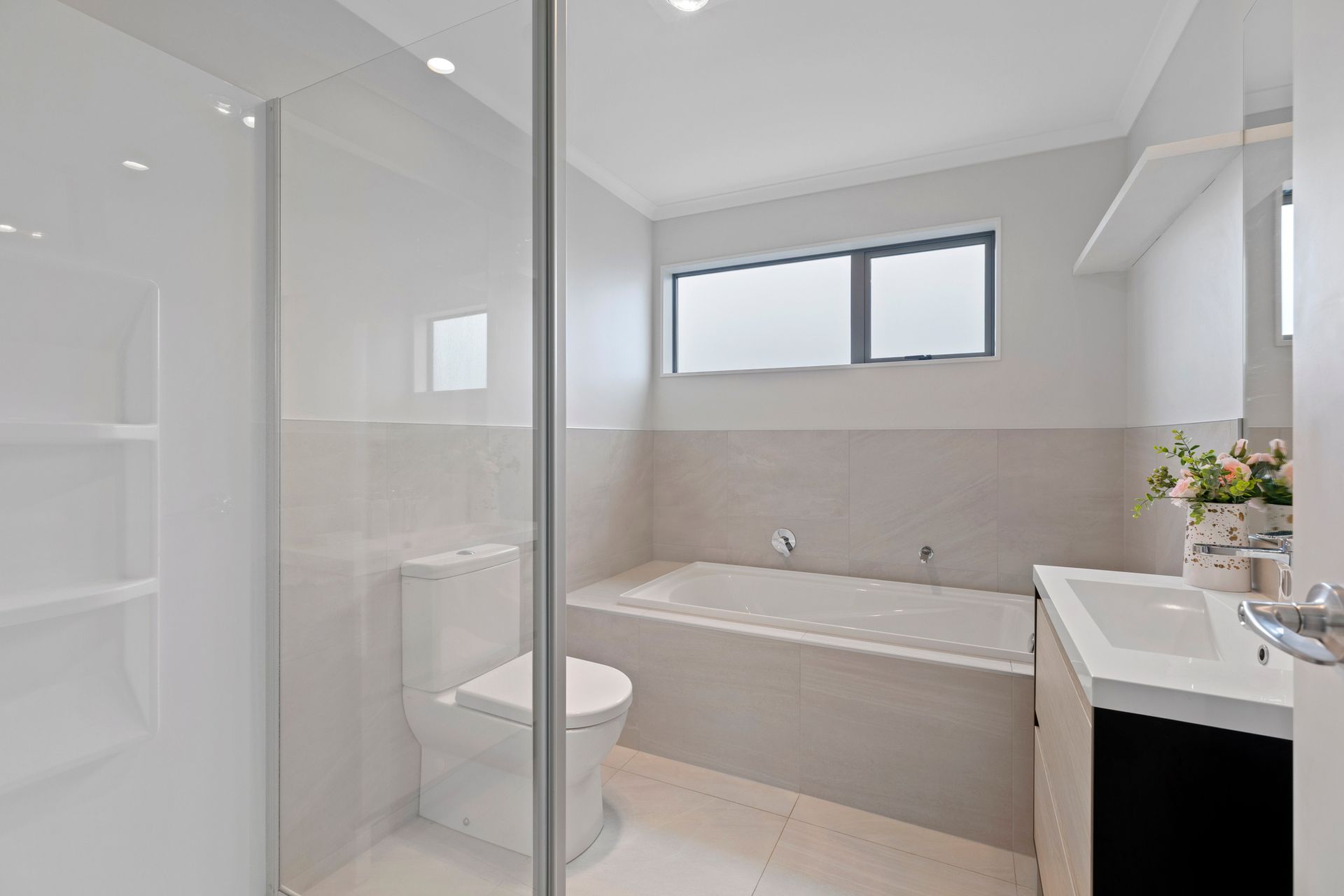 Modern bathroom with white walls, bathtub, toilet, sink, and glass shower.