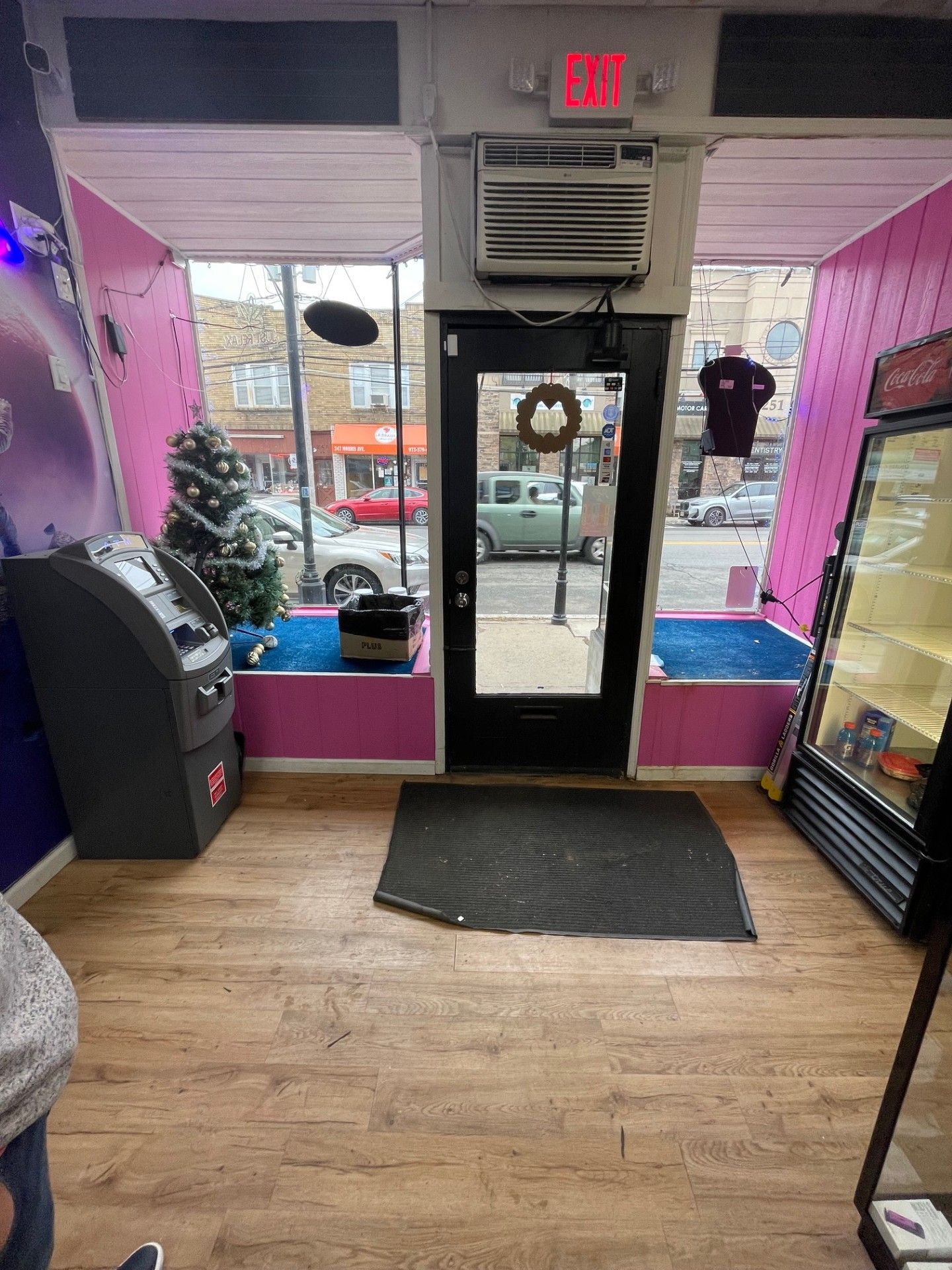 The inside of a store with a pink wall and a black door.