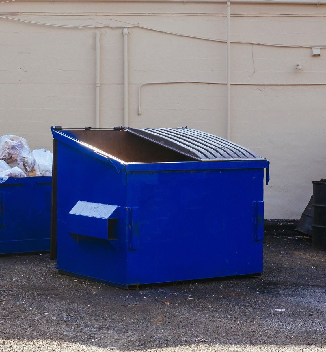 A blue dumpster is sitting in a parking lot