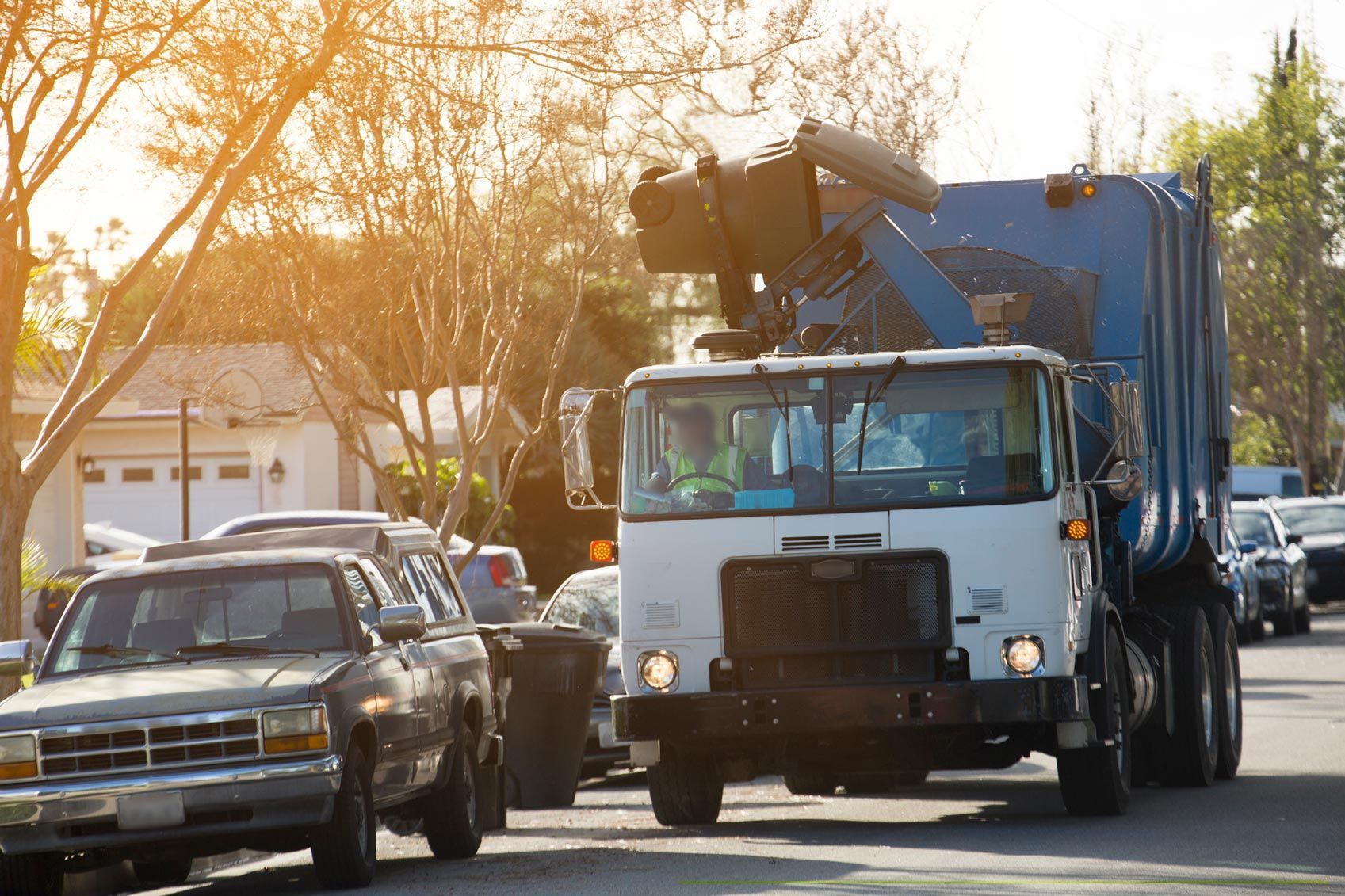 A garbage truck is driving down a residential street.
