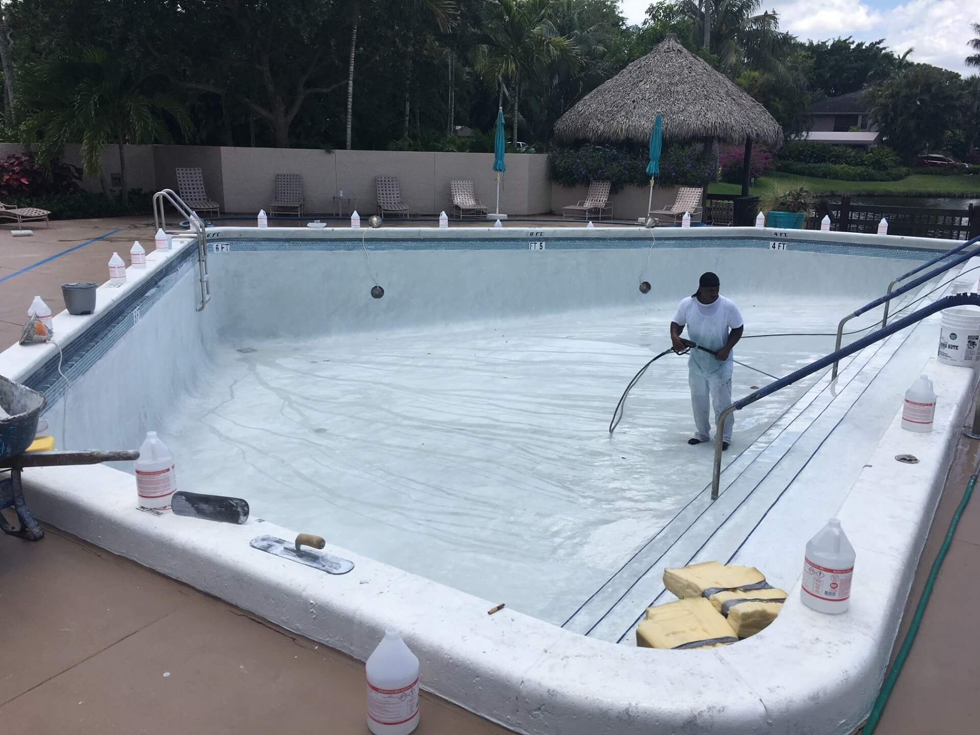 A man is cleaning a swimming pool with a hose.