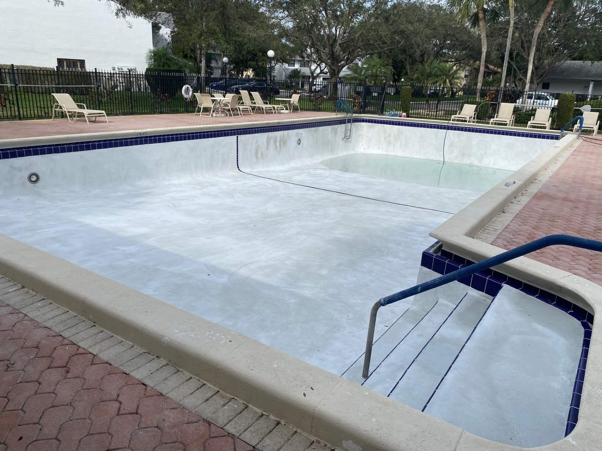 An empty swimming pool with stairs leading to it.
