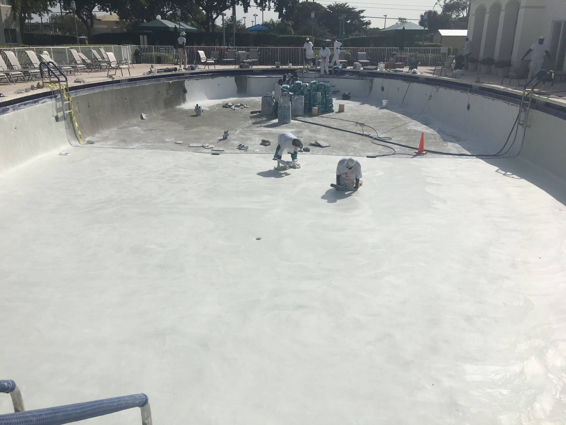 A large swimming pool is being remodeled by a group of people.