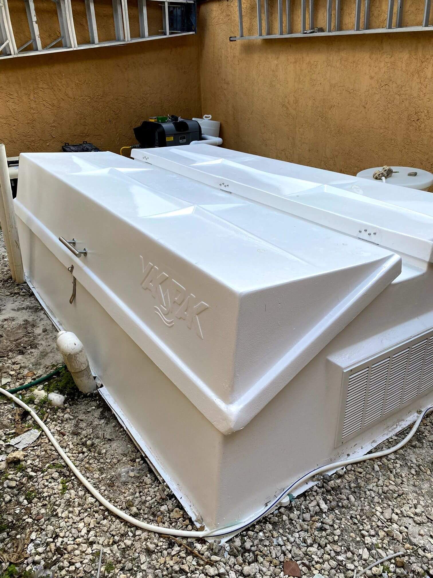 A white box is sitting on the ground next to a ladder.