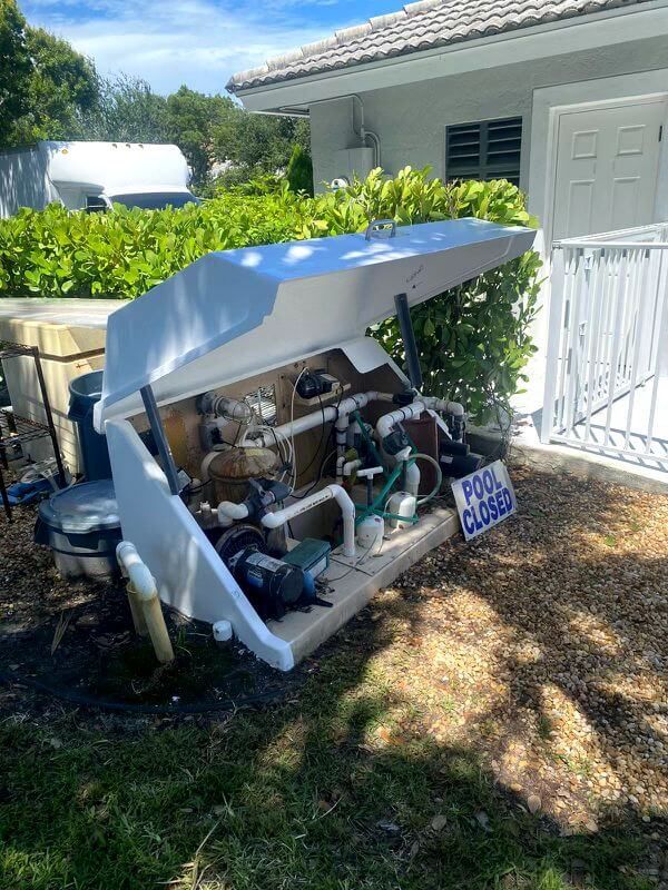 A swimming pool pump is sitting in a box in front of a house.