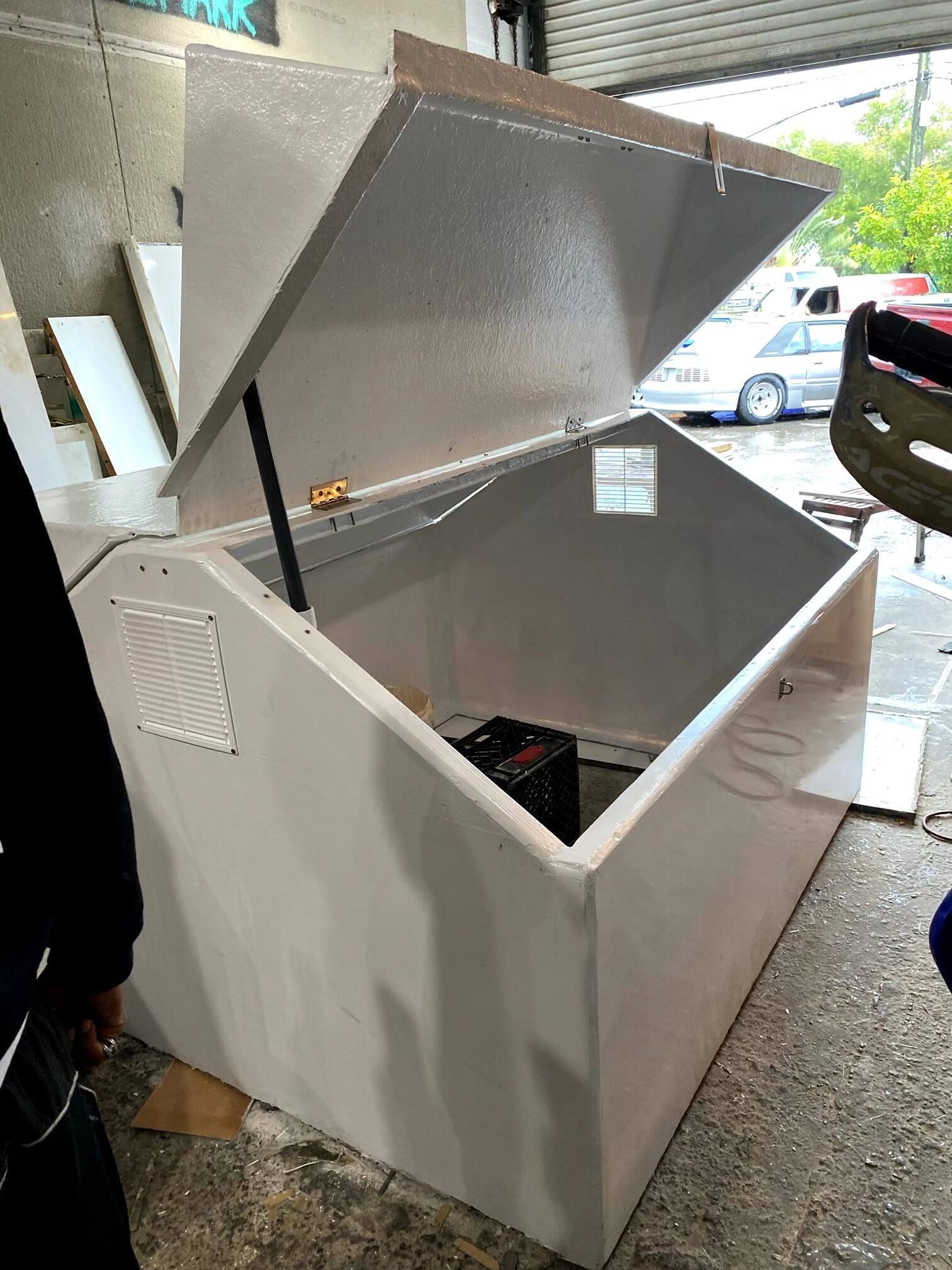 A person is standing next to a white box with the lid open.