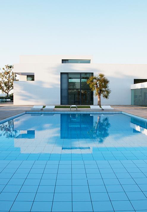 A large white house with a swimming pool in front of it.