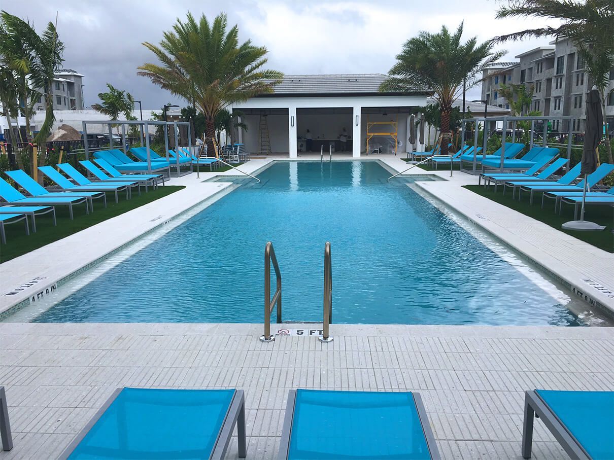 A large swimming pool surrounded by blue chairs and palm trees.