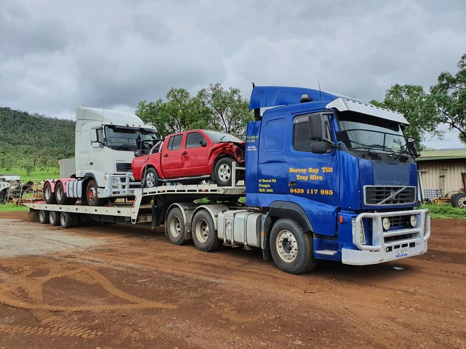 A Blue Semi Truck is Carrying Two Cars on a Flatbed Trailer — Hervey Bay Tilt Tray Hire In Takura, QLD