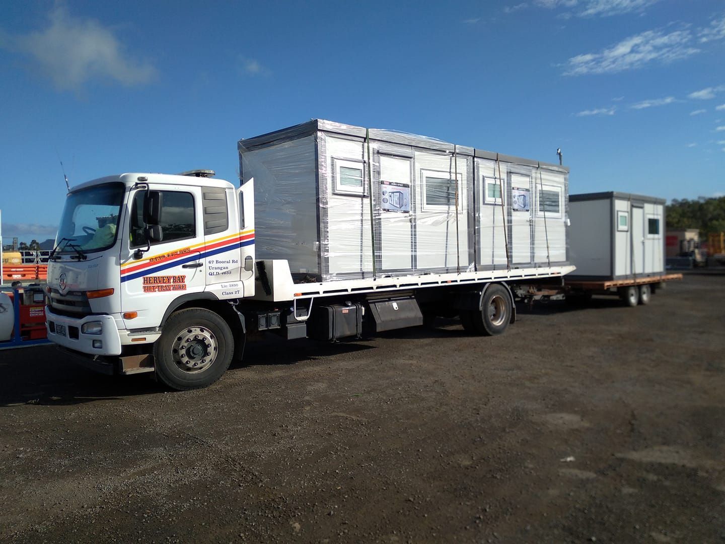 A Truck is Carrying a Trailer With a Bunch of Containers on It — Hervey Bay Tilt Tray Hire In Maryborough, QLD