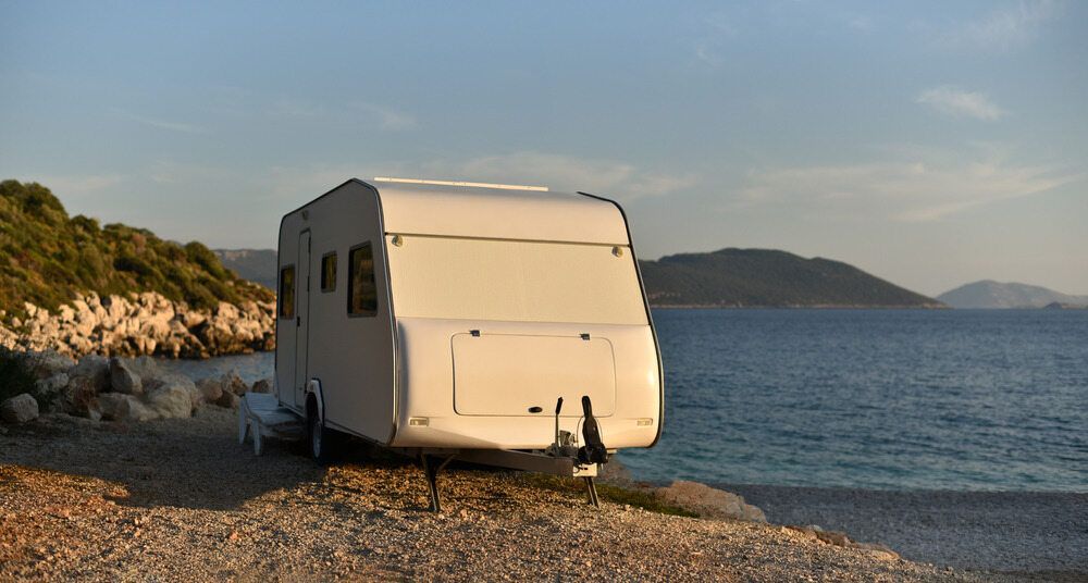 A White Trailer is Parked on the Beach Next to the Ocean — Hervey Bay Tilt Tray Hire In Takura, QLD