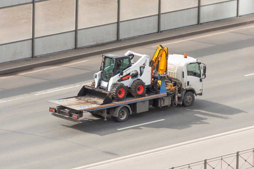 A Tow Truck is Carrying a Bulldozer on the Back of It — Hervey Bay Tilt Tray Hire In Takura, QLD