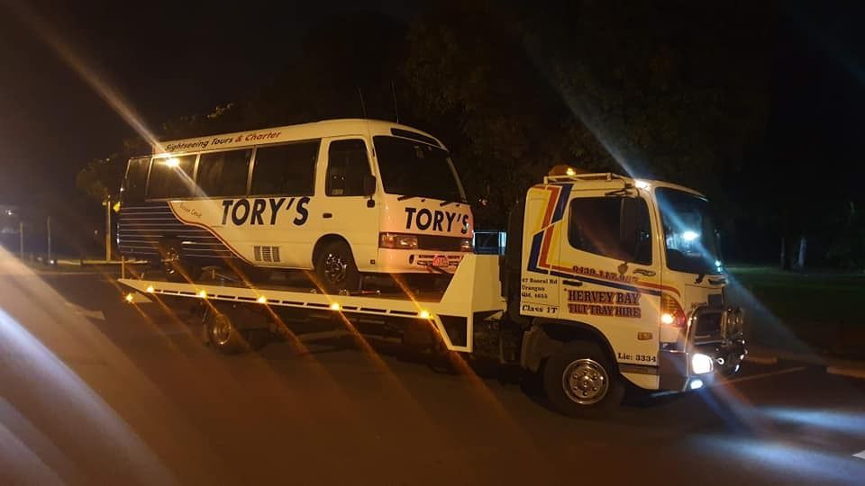 A White Van is Being Towed by a Tow Truck at Night — Hervey Bay Tilt Tray Hire In Bundaberg, QLD