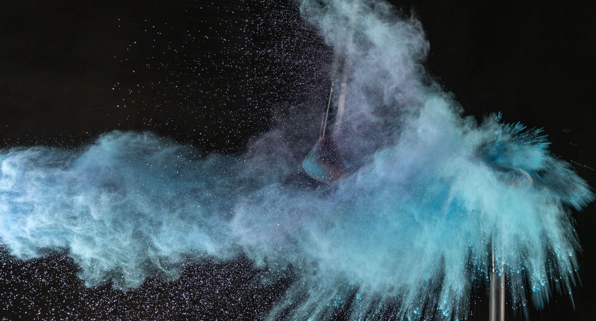 Blue powder cloud exploding against a black background