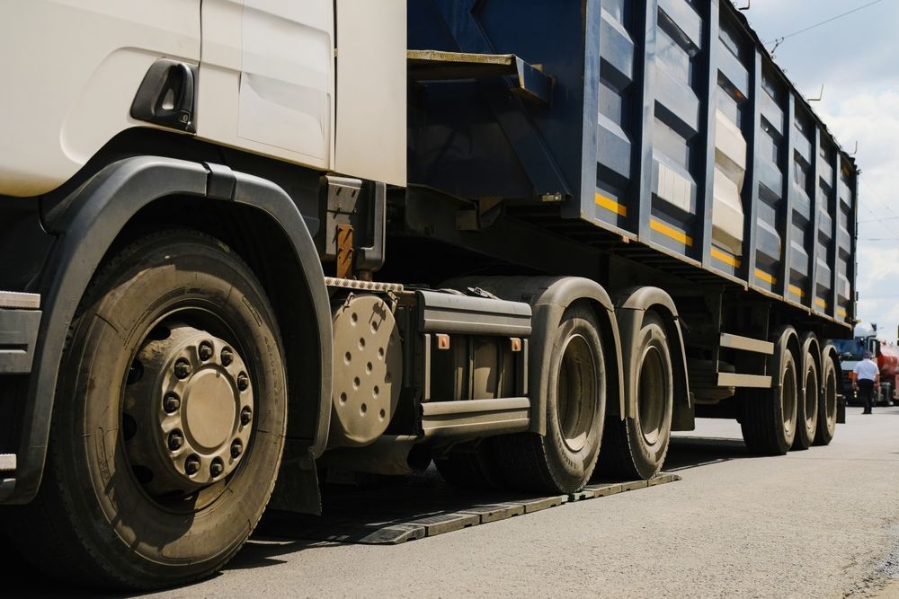 A large, white semi-truck with a blue dump trailer parked on an asphalt surface.