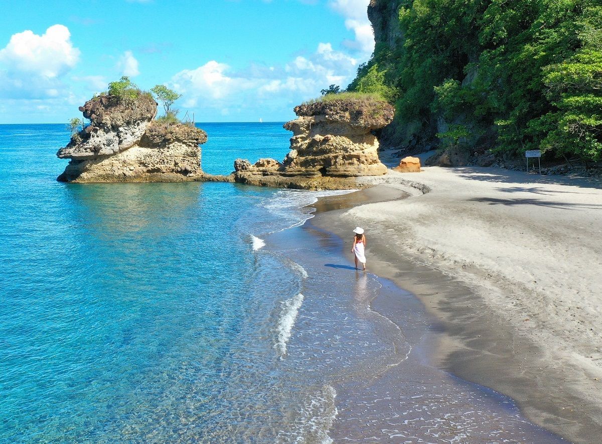 A person is standing on a beach near the ocean.