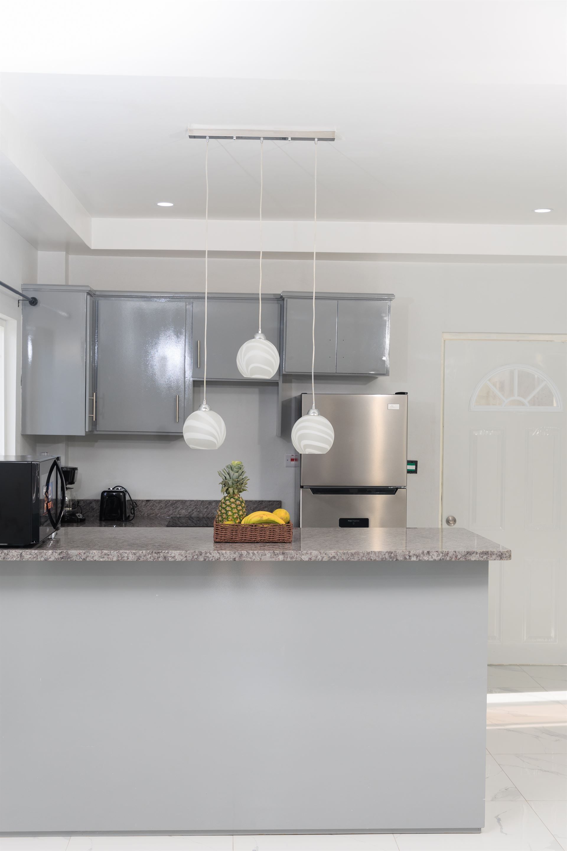 A kitchen with gray cabinets , a stainless steel refrigerator , and a large island.