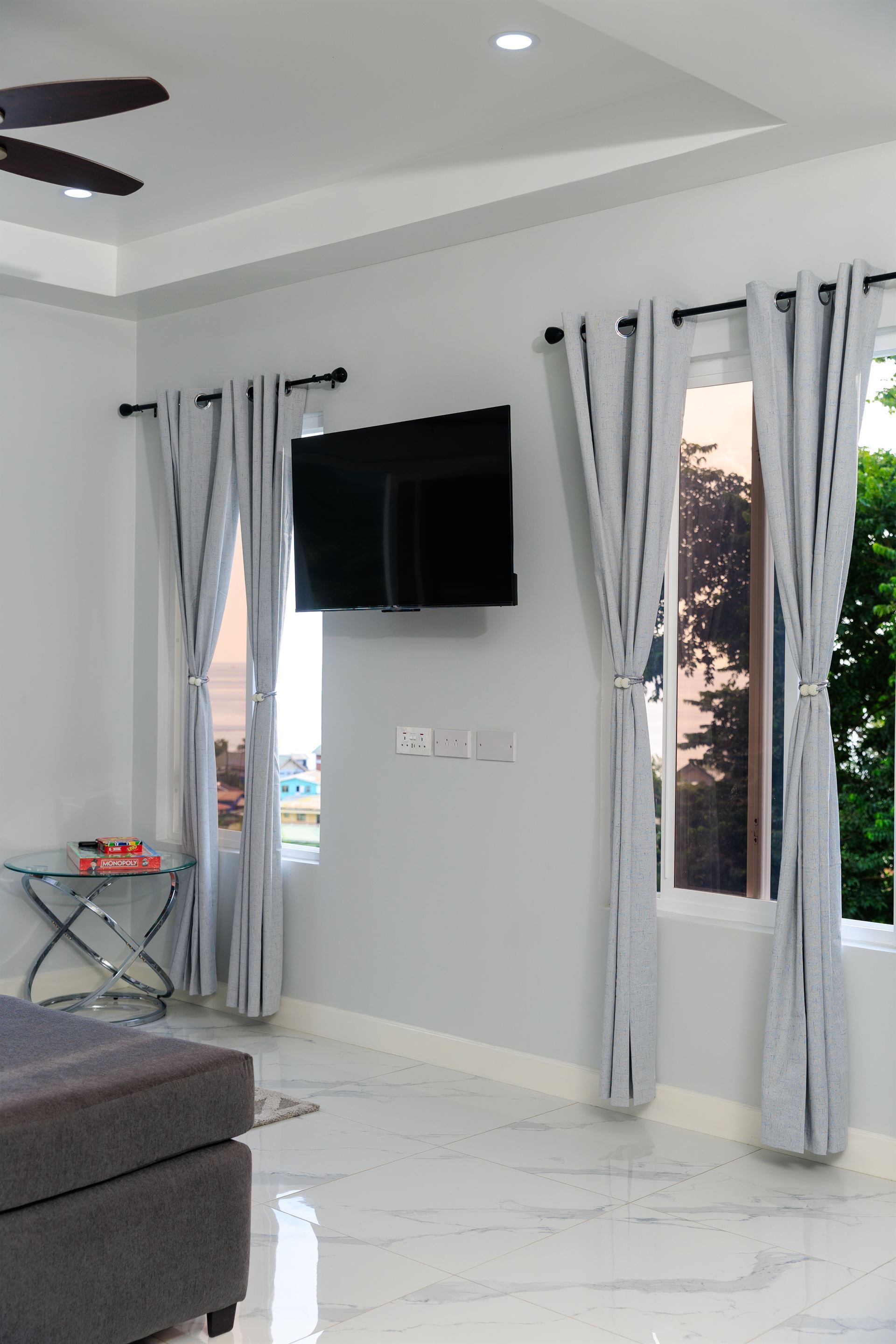 A living room with a flat screen tv and a ceiling fan.