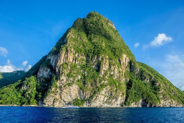 A large mountain is surrounded by water and trees.