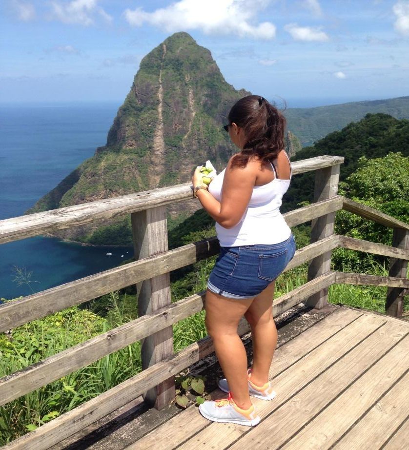 A woman standing on a wooden deck looking at a mountain