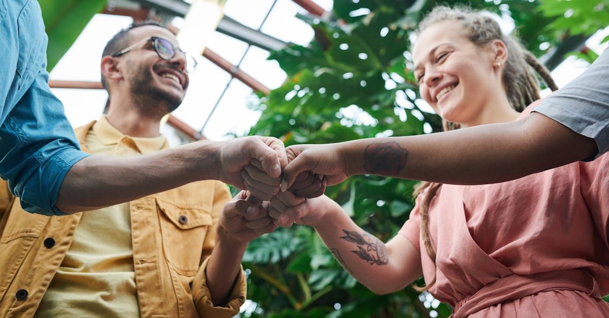 A group of people are putting their hands together in a greenhouse.