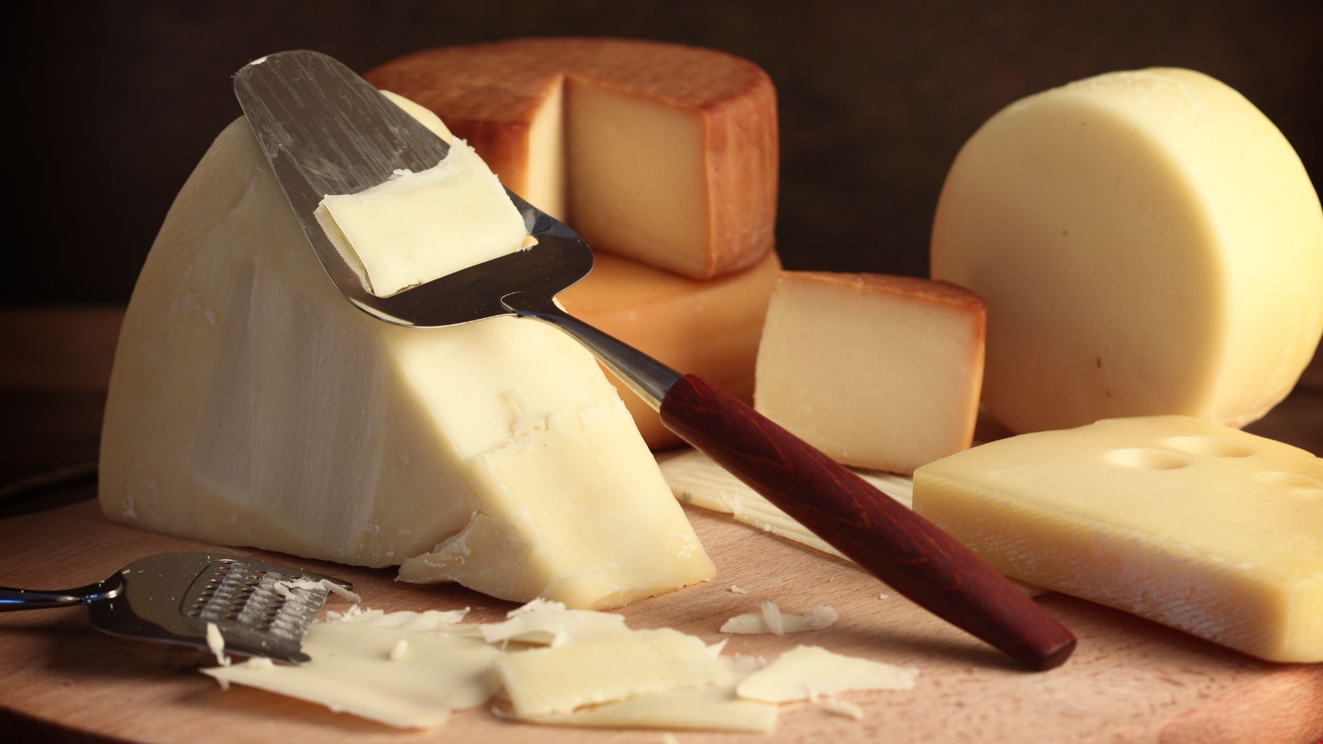 There are many different types of cheese on the cutting board.