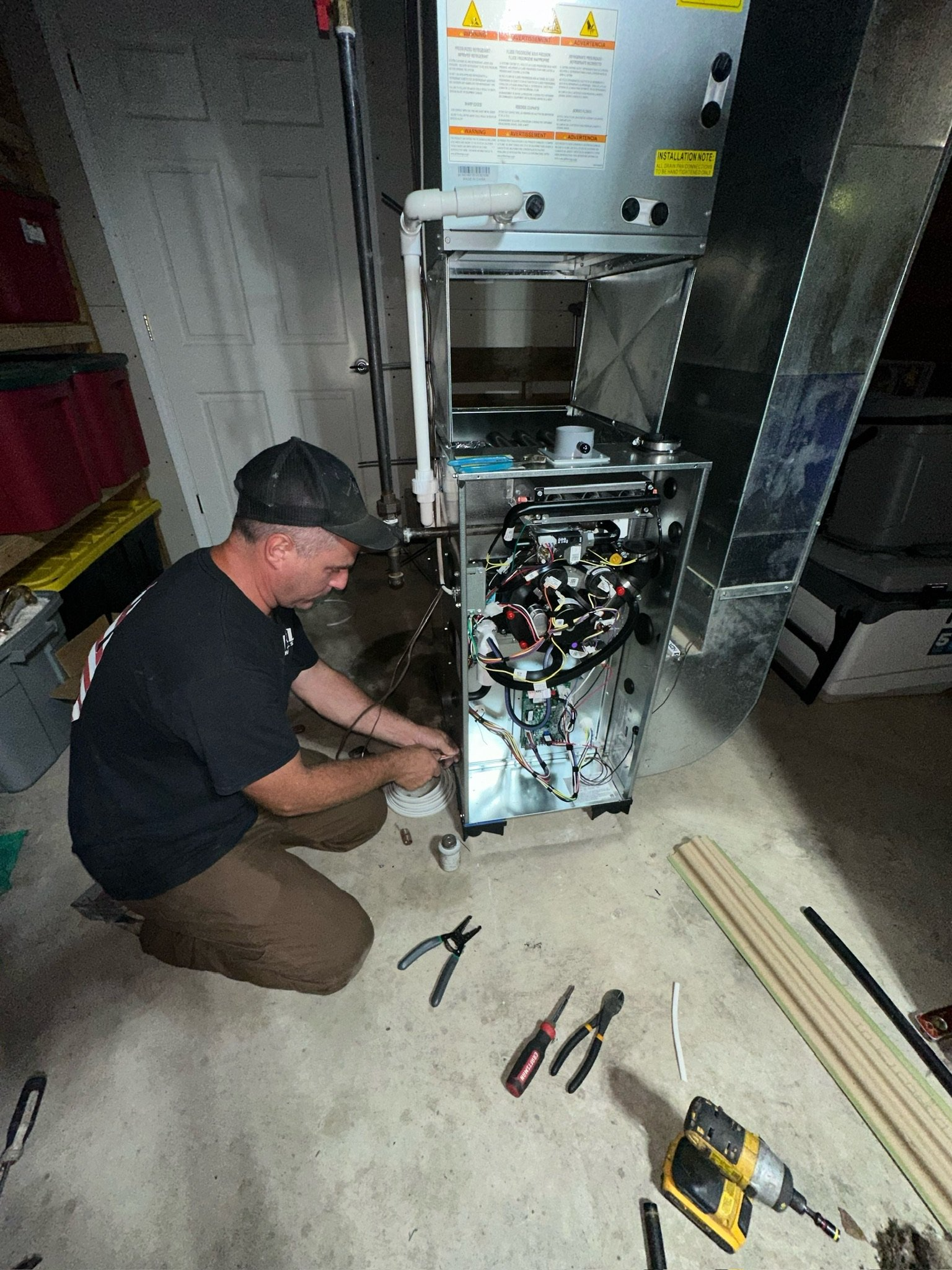 A man is working on a heating system in a basement.