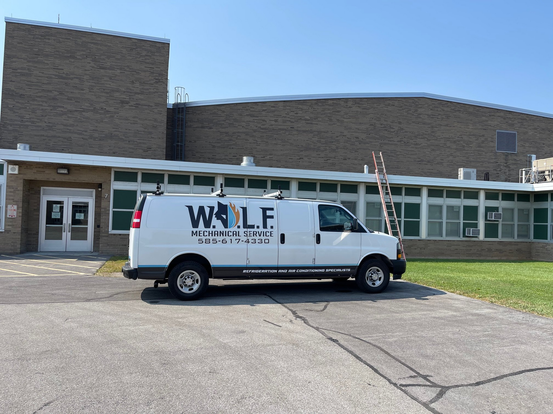 A white van with the word wolf on it is parked in front of a building.