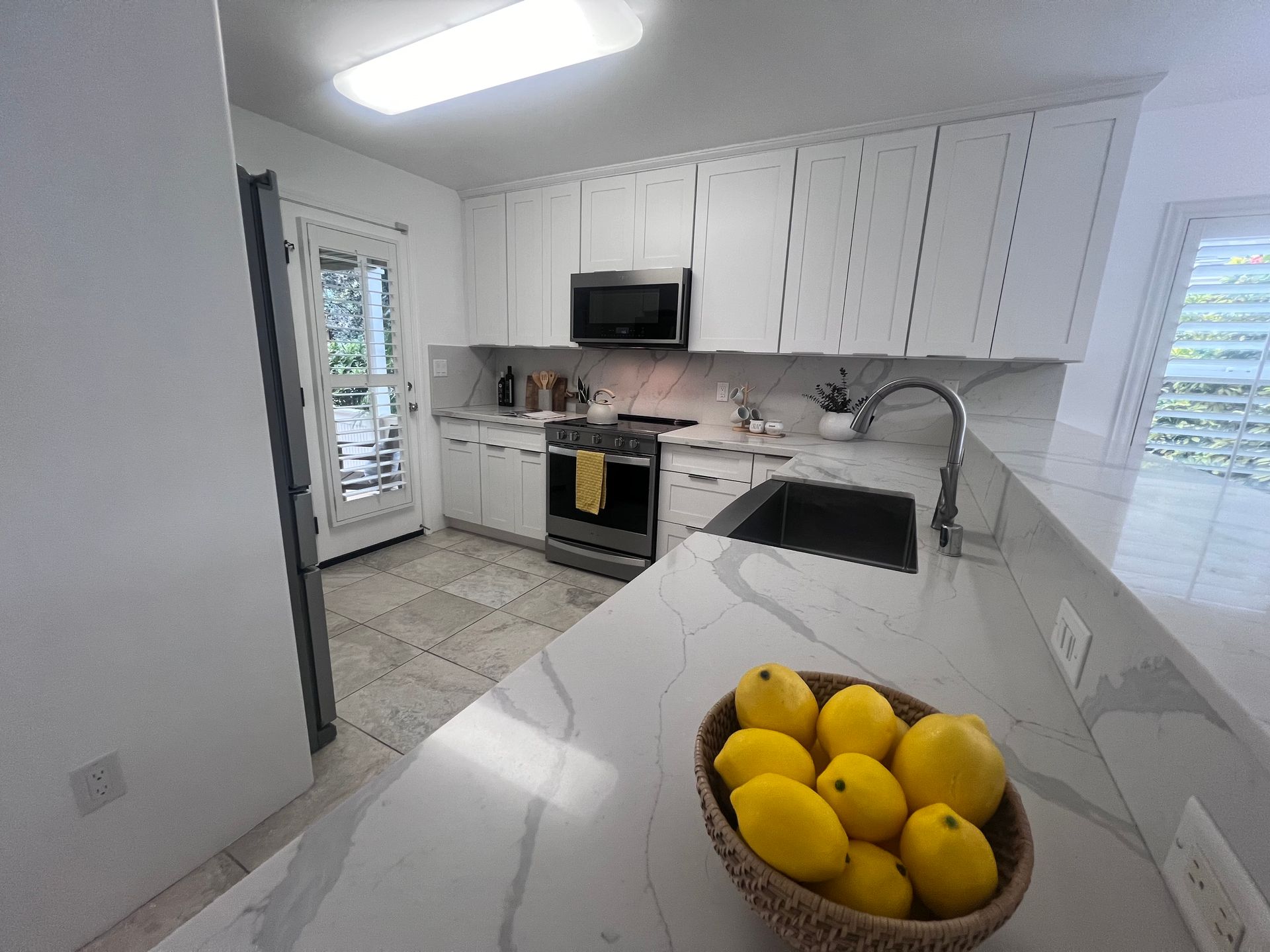 A kitchen with white cabinets and a bowl of lemons on the counter.