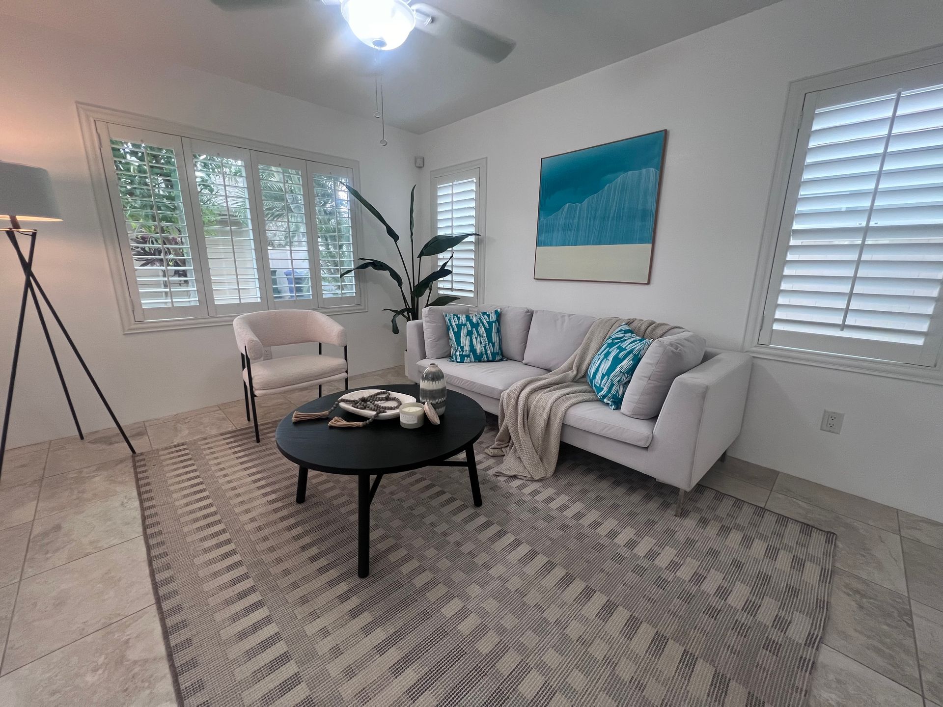 A living room with a couch , table , chairs and a painting on the wall.