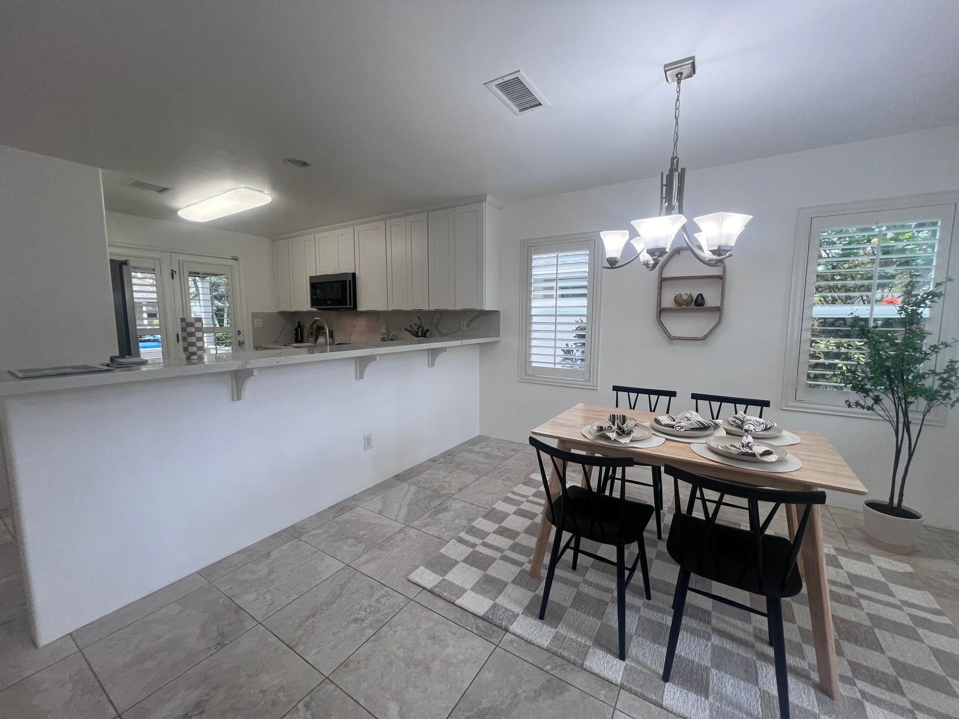 A dining room with a table and chairs and a kitchen in the background.