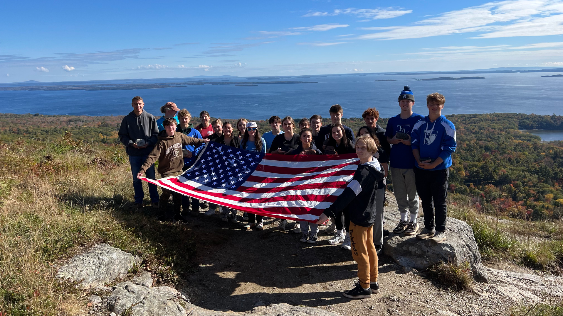 Students on a mountain holding U.S. flag