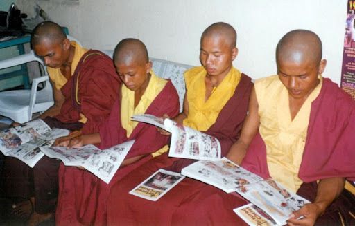 Tibetan monks appear fascinated by a Bible story comic book. [VOM Canada]