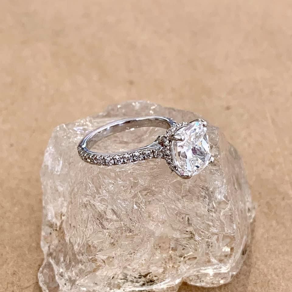 Diamond engagement ring on a clear, textured rock against a beige background.