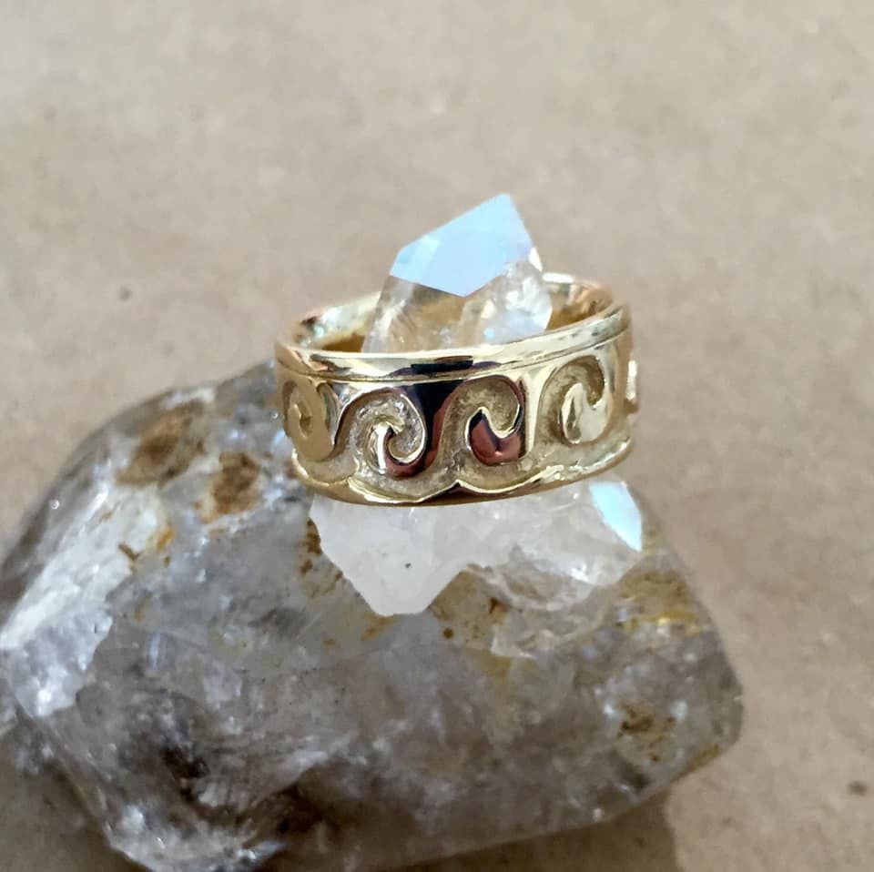 Gold ring with wave design, displayed on a quartz crystal formation.