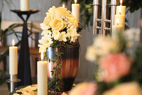 a urn filled with flowers and candles is sitting on a table .