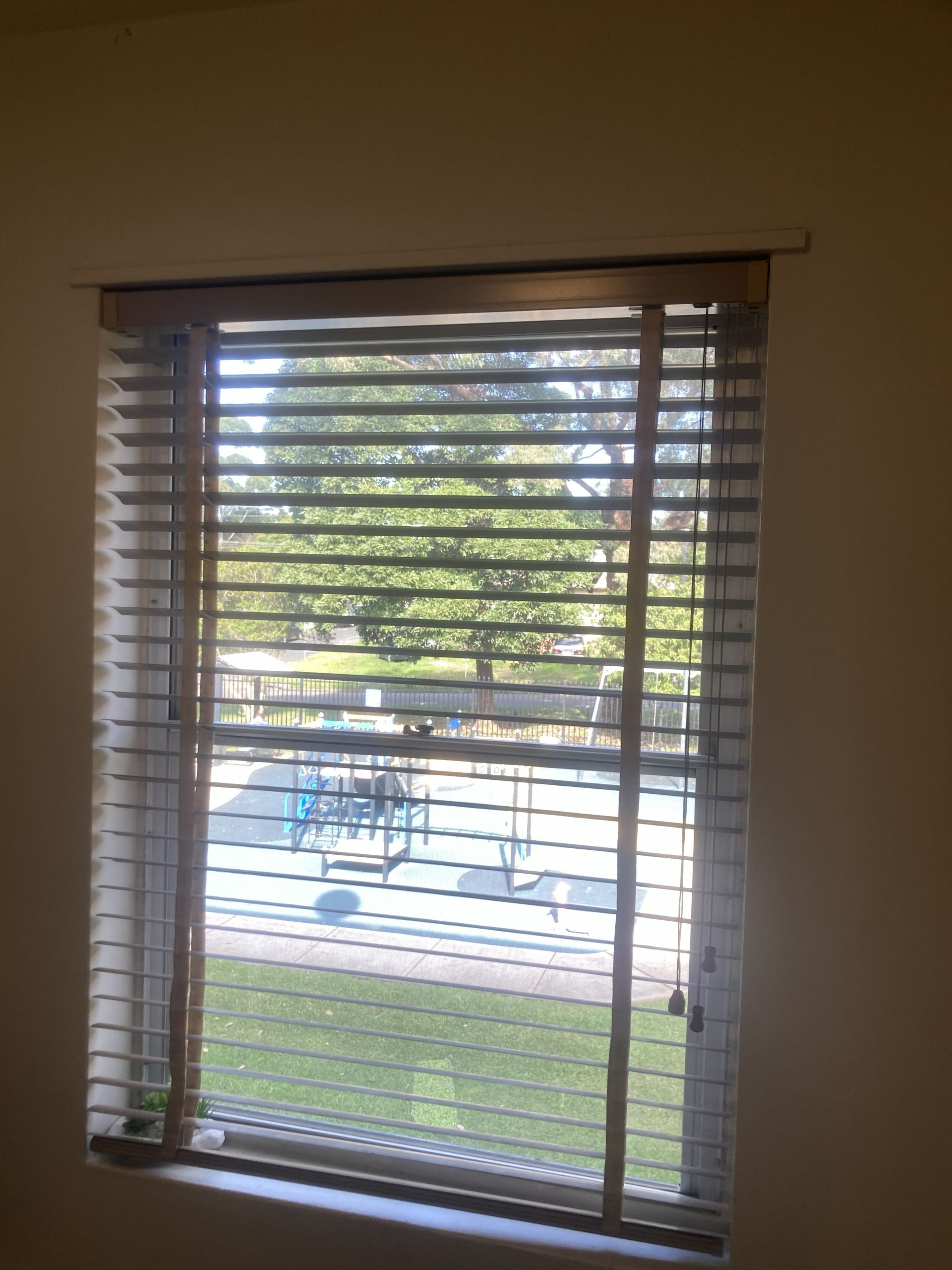 Close-up of brown window blinds with light filtering through the slats