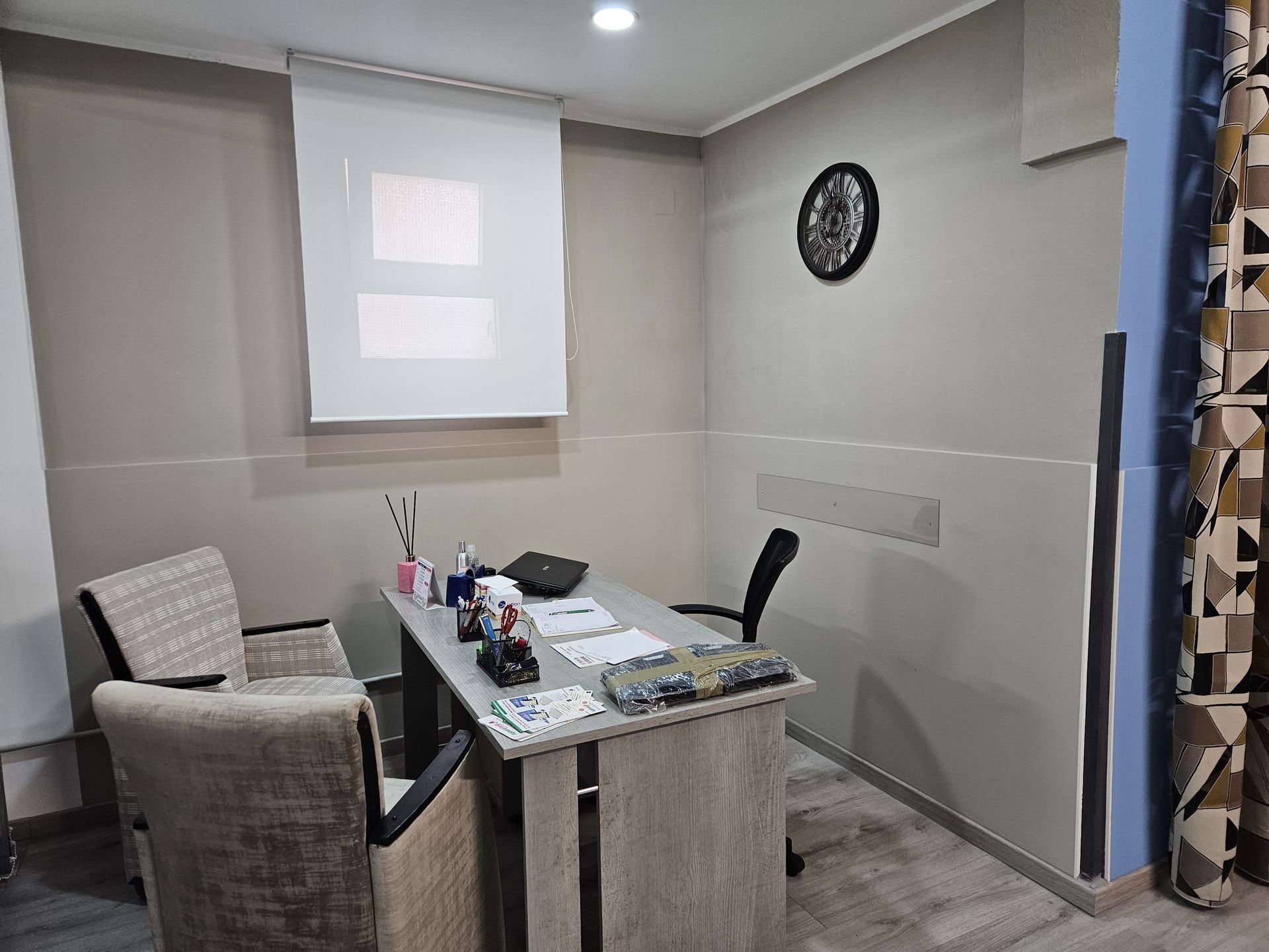 Una stanza con un tavolo, delle sedie e un orologio sul muro.