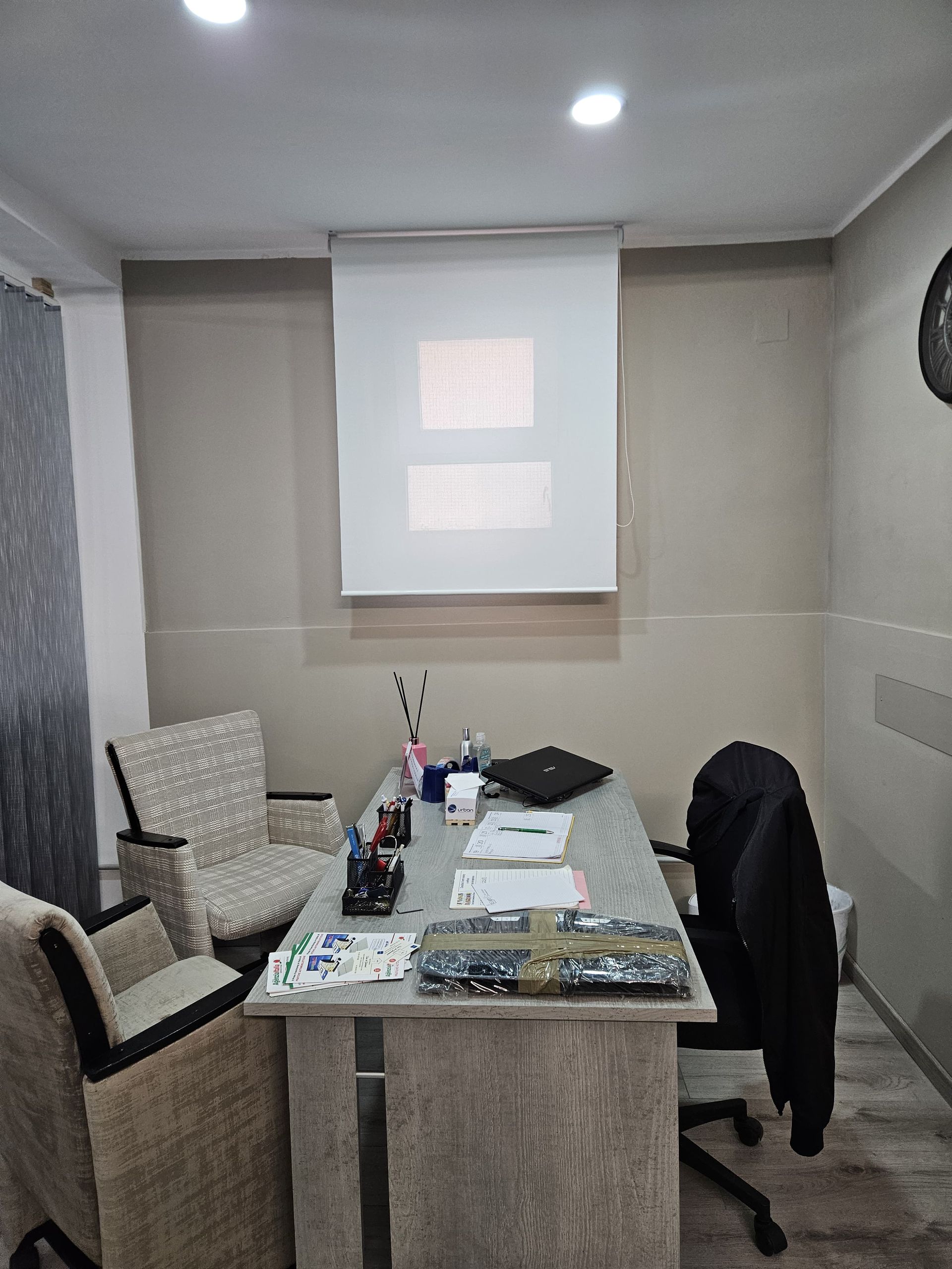 Una stanza con una scrivania, sedie e uno schermo per proiettore.