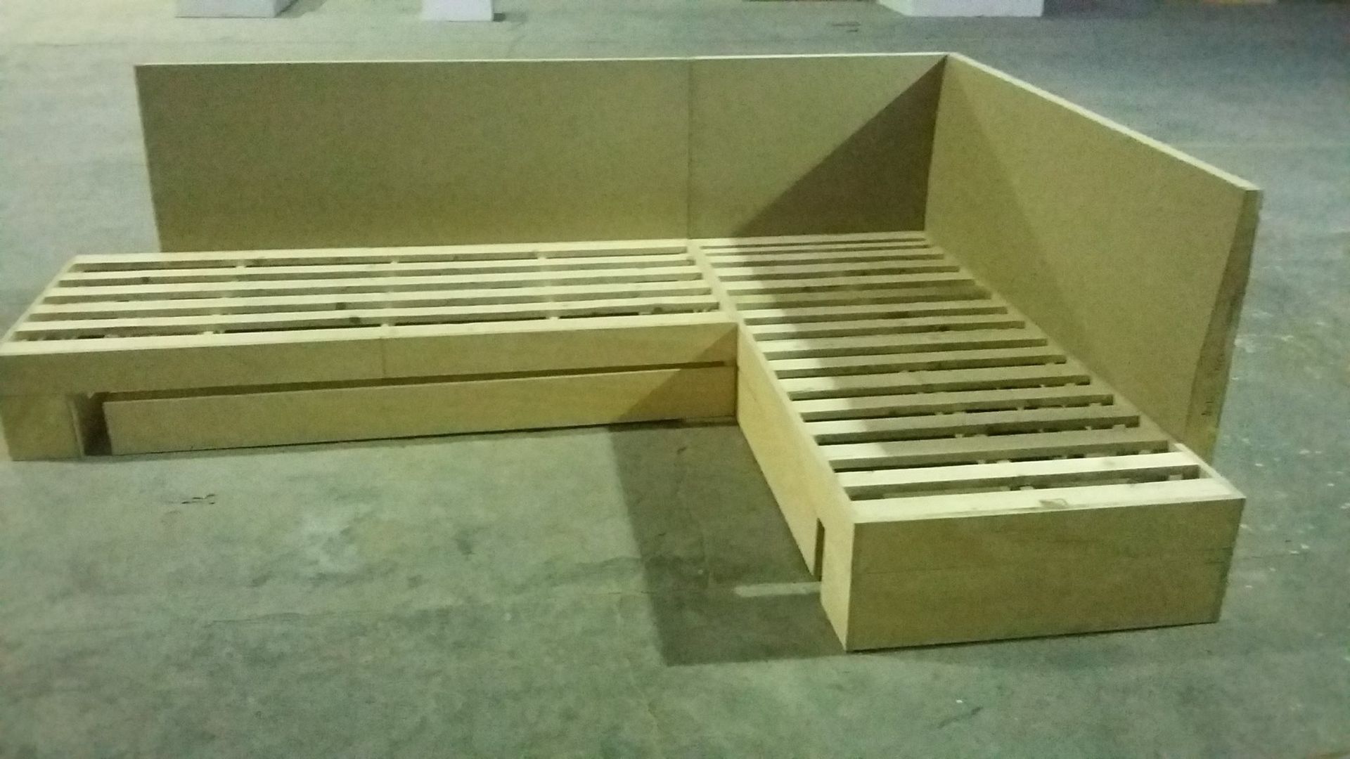 Un divano di cartone è appoggiato su un pavimento di cemento