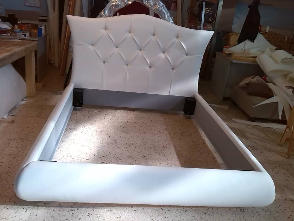 Un letto bianco è appoggiato su un pavimento piastrellato in una stanza