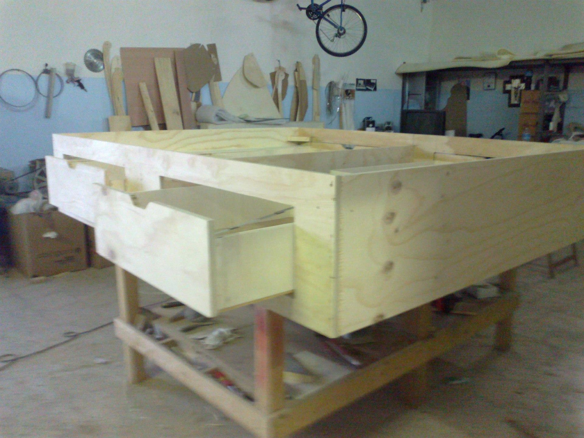 Un tavolo di legno con cassetti e una bicicletta sullo sfondo