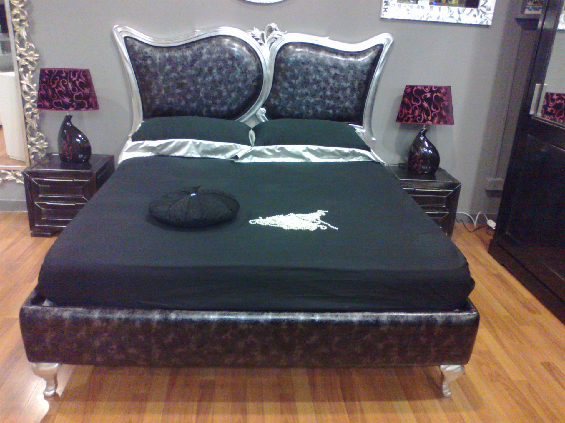 Un letto con lenzuola e cuscini neri in una camera da letto