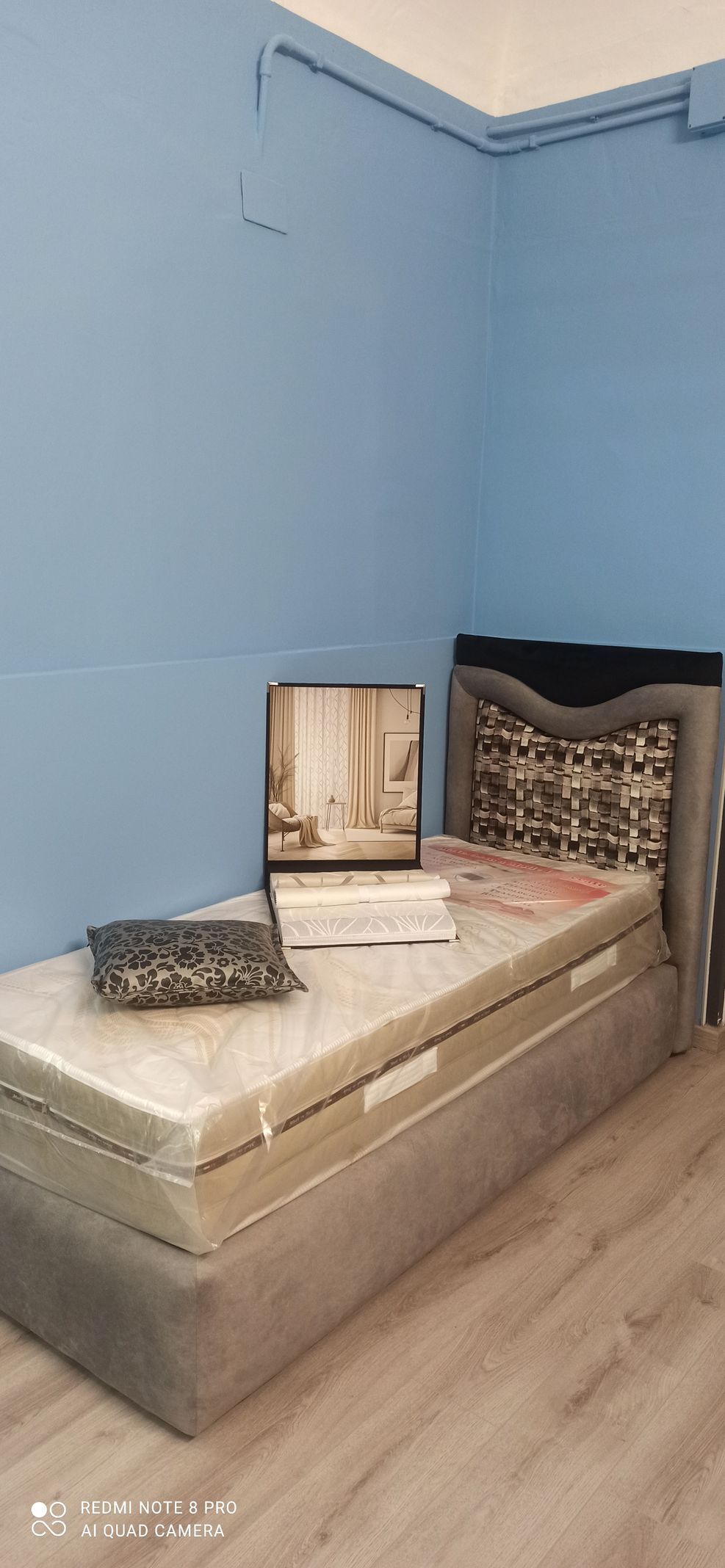 Un letto con un materasso sotto in una stanza con le pareti blu.