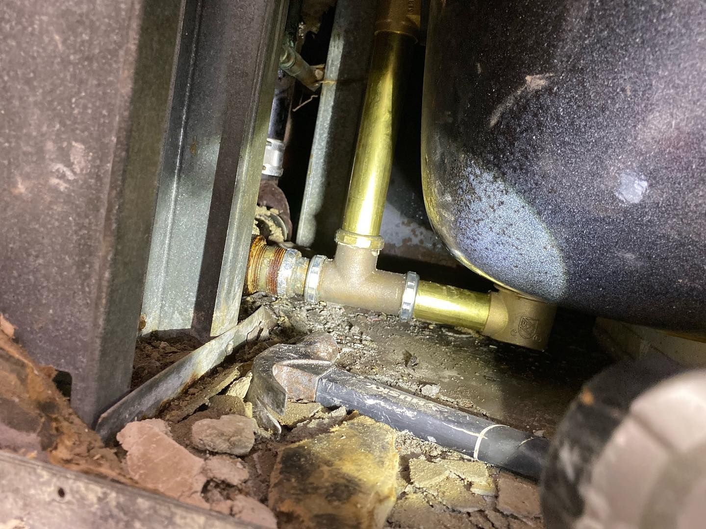 Brass plumbing fittings in a cramped space, with a rusted pipe connection.